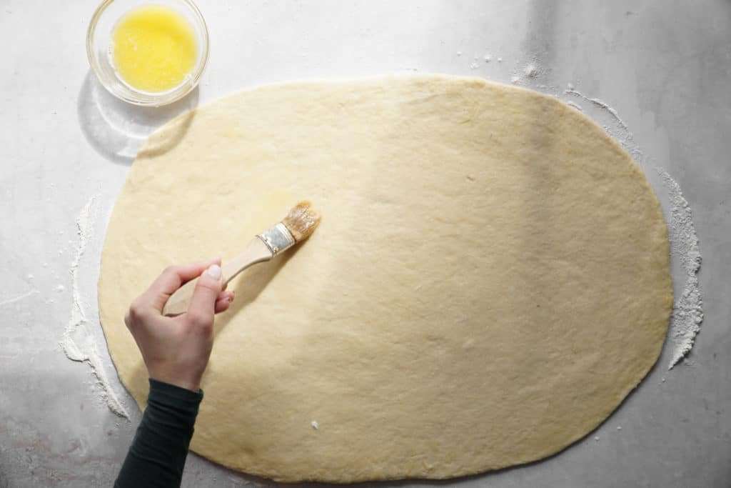 Spreading butter on dough for easy homemade cinnamon buns.